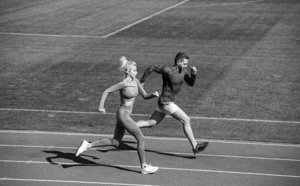 Спортсменка и мужчина спринтеров бегают по беговой дорожке на стадионе, выносливость — стоковое фото