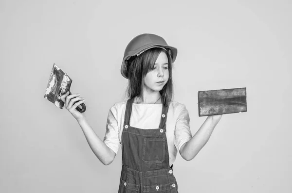 Lets start. renovation and repair. using working tool. teen girl in helmet and boilersuit with spatula. child wear hard hat. kid builder on construction site. worker engineer. architect in workshop — Stock Photo, Image