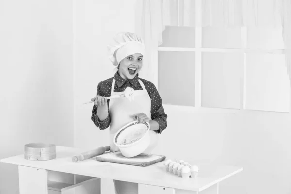 Menina criança feliz no chapéu cozinheiro e avental na cozinha, padeiro — Fotografia de Stock