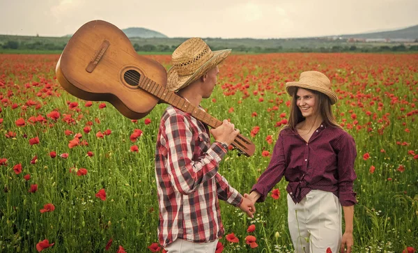 恋爱中的一对快乐的情侣，在美丽的罂粟花田里，用音响吉他、亲属关系来放松一下 — 图库照片
