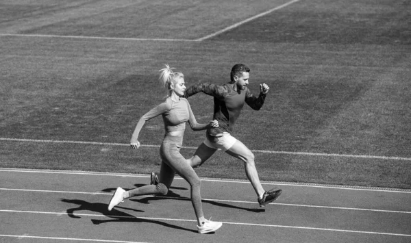 Атлетичный мужчина и женщина спринтеров бегают по беговой дорожке на стадионе, выносливость — стоковое фото