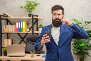 Gaddar takım elbiseli CEO sabah kahve fincanını ofiste tutar, kahve molası verir.