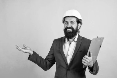 Foreman müfettişi. İnşaat projesinde çalışıyorum. Sakallı mutlu adam sert şapka takıyor. Mühendislik kavramı. Mimari ve bina. Erkek müteahhit koruma için resmi takım elbise ve kask giyiyor.