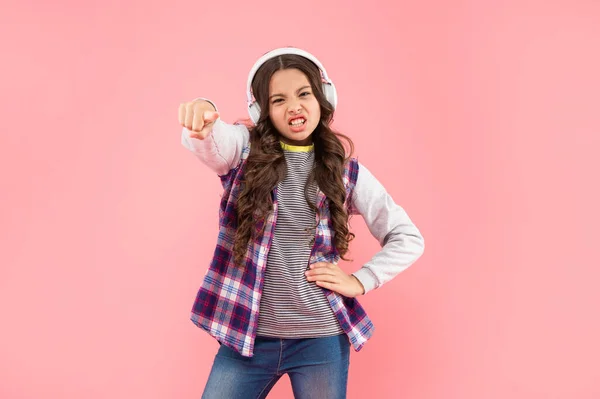 Arg barn lyssna musik i hörlurar på rosa bakgrund, tillbaka till skolan — Stockfoto