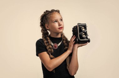 Retro kameralı şık bir çocuk beyaz fotoğraflarla izole edilmiş bir fotoğraf çekiyor.