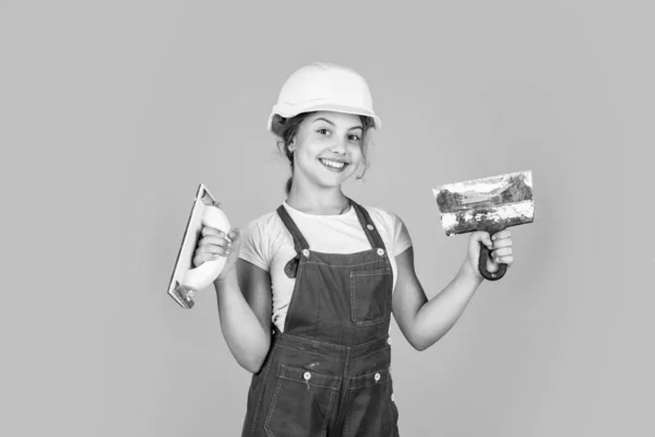 Готов к работе. Счастливая девушка использует шпатель инструмент. строитель-подросток носит защитный шлем. молодой работник в защитной каске. уверенный в себе ребенок использует лопатку во время ремонта. концепция строительства и реконструкции — стоковое фото