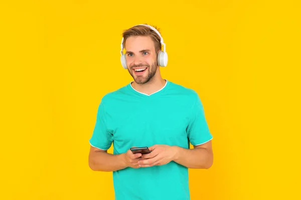 Happy young man in green tshirt listening to music on mobile phone with headphones, enjoy — Stock Photo, Image