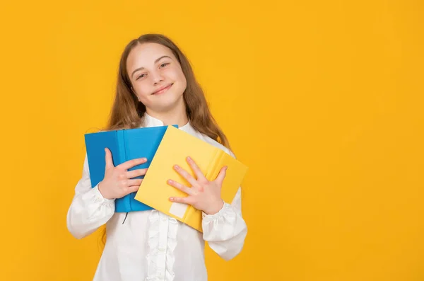 Χαρούμενο παιδί κρατήσει το βιβλίο του σχολείου σε κίτρινο φόντο με αντίγραφο χώρου, εκπαίδευση — Φωτογραφία Αρχείου