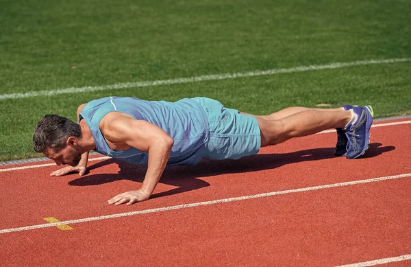Muskulöse Mann stehen in Planke macht Liegestütze auf Sporttraining, Energie — Stockfoto