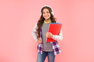 Mutlu çocuk, kulaklıkla müzik dinle. Pembe arka plan, eğitim üzerine çalışma kitabı tut.