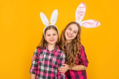 Sarı arka planda tavşan kulaklı mutlu Paskalya çocukları