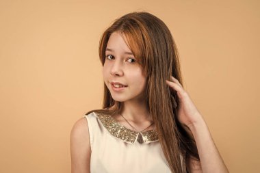 Kumral saçlı hoş bir genç kız. Yeni saç stili. Uzun saçlı neşeli bir çocuk. Çocuk için kuaför konsepti. Çocuk modası ve güzellik. Mutlu çocukluk. Doğal gençlik güzelliği