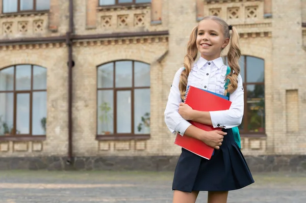 Feliz escolar en uniforme de vuelta a la escuela llevando libros y mochila, espacio para copiar — Foto de Stock