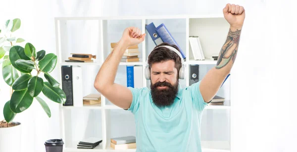 Счастливый парень делает победный жест слушая наушники в офисе, музыку — стоковое фото