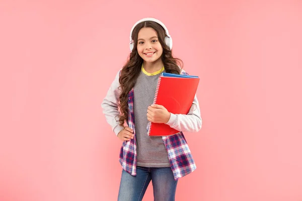 Szczęśliwy dziecko słuchać muzyki w słuchawkach trzymać skoroszyt na różowym tle, edukacja — Zdjęcie stockowe