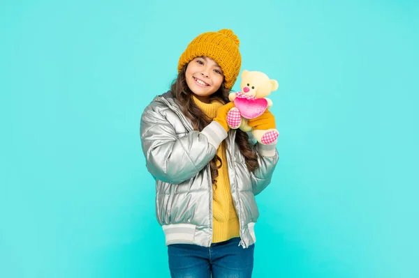 Весела дитина в капелюсі і рукавичках тримає іграшку на синьому фоні, день валентинки — стокове фото