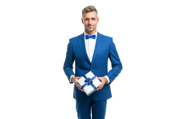 Hombre sonriente en traje de pajarita azul sostiene la caja actual aislada en blanco — Foto de Stock