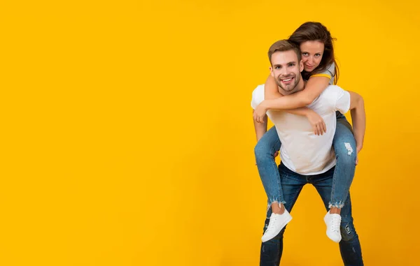 Feliz romántico pareja tener divertido haciendo piggyback paseo amarillo fondo copia espacio, amor —  Fotos de Stock