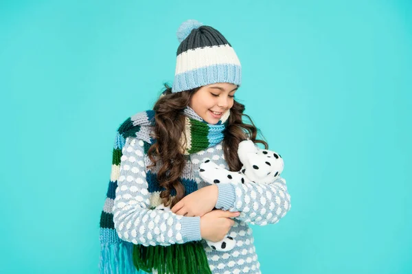 Positivt barn i stickade kläder ta hand om leksaken. tonåring flicka på blå bakgrund. lycklig barndom. — Stockfoto