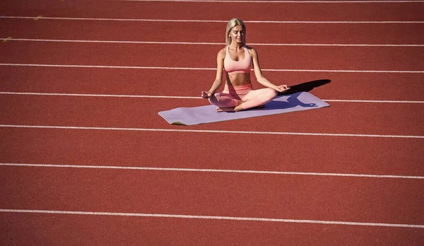 Mulher esporte em sportswear praticando ioga no estádio pista de corrida antes de treinar fitness, meditação — Fotografia de Stock