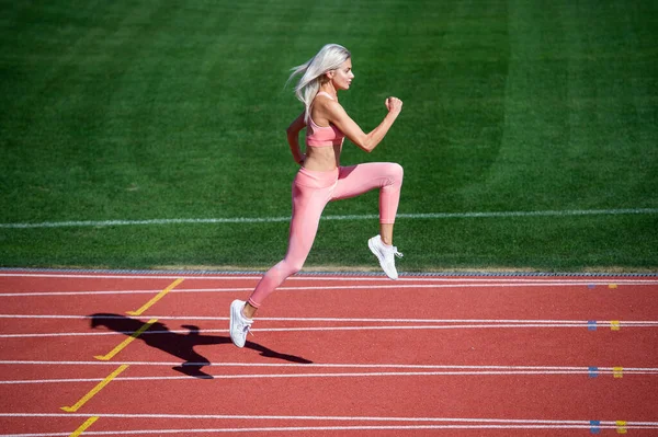 Fit lady w stroju fitness działa na stadionie tor wyścigowy podczas treningu sportowego, prędkość — Zdjęcie stockowe