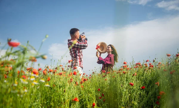 Hombre con cámara y mujer en el campo de amapola. prado de flores de verano. — Foto de Stock