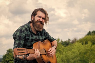 Tişörtlü, beyaz, vahşi hippi akustik gitar çalıyor.