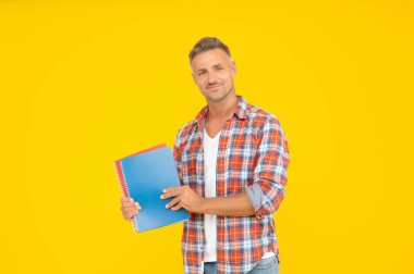 Eğitim için kitapları tutan mutlu üniversite öğrencisi sarı arkaplan, kopyalama alanı