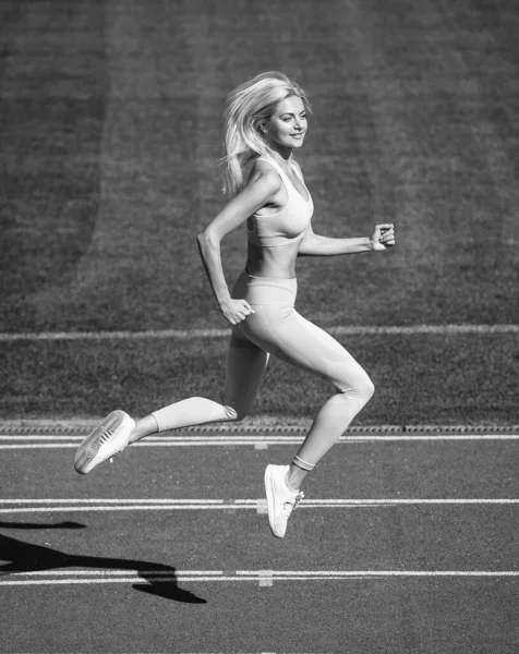 Zayıfla. Hız ve enerji. Dayanıklılık. Spor giyim sektöründe seksi bir koşucu. Açık hava arena pistinde koşuyor. Antrenman ve antrenman. Atletik bayan antrenör koşuyor. Hareket halindeki kadın spor eğitmeni — Stok fotoğraf