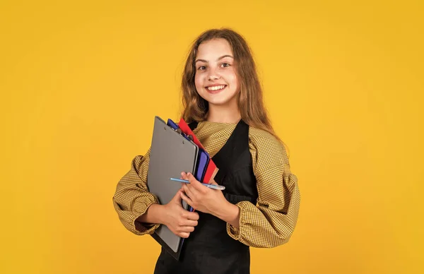 Snygg barnflicka som arbetar med pappersdokument i mapp, tillbaka till skolan — Stockfoto
