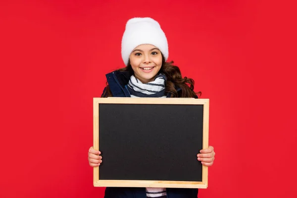 Miúdo feliz com quadro-negro de chapéu. menina adolescente segurando quadro com espaço de cópia. criança de volta à escola. — Fotografia de Stock