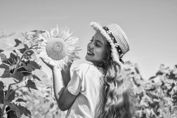 Infanzia felice. Il ragazzo indossa un cappello estivo di paglia. bambino in campo di fiori gialli. ragazza adolescente nel campo di girasole. concetto di vacanza estiva. raccolto ricco e agricoltura. Fertile presente — Foto Stock