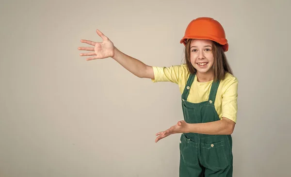Девочка в каске на стройке, представляет продукт, копирует пространство для рекламы — стоковое фото
