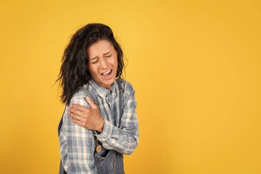 Çok acıtıyor. Korkunç bir acı. Kadının omzu zedelenmiş. Kadın koluna vurmuş. Kız ağlıyor. Acı verici tedavi. İlaca ihtiyacım var. Kırık kol. Mutsuz kadın omuz ağrısı çekiyor.