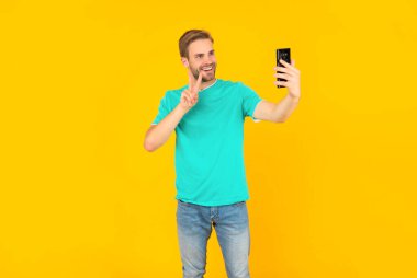 Cep telefonlu video blogcusu barış jesti gösteriyor. Akıllı telefondan video blogu yapan adam.