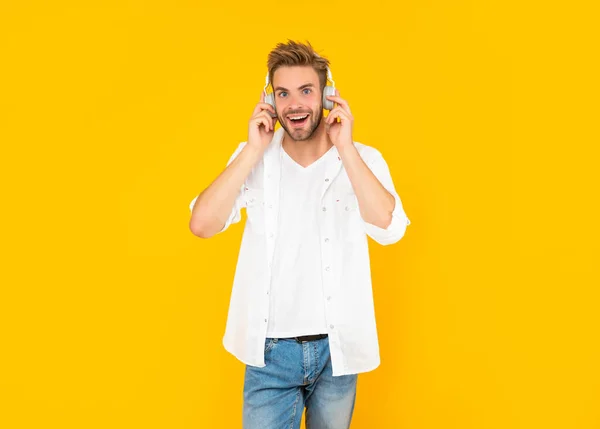 Feliz joven sin afeitar en los auriculares sobre fondo amarillo, la moda — Foto de Stock