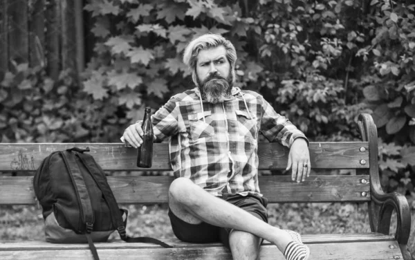 현대의 사냥꾼이 휴식을 취한다. 넌 휴식을 취할 자격이 있어. 맥주굽기. 수염 남자가 차가운 신선 한 맥주 병을 들고 있습니다. 공원에서 맥주를 즐기는 남자. 여름 방학 컨셉트. 공원에서 맥주를 마시는 벤치에 앉아 있는 남자 — 스톡 사진