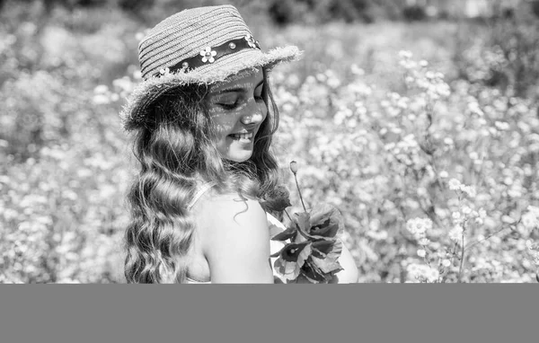 Feliz niña pequeña con aspecto de belleza use sombrero de sol en el pelo largo y rizado rubio sosteniendo flores de amapola en el paisaje natural soleado de verano, salón — Foto de Stock