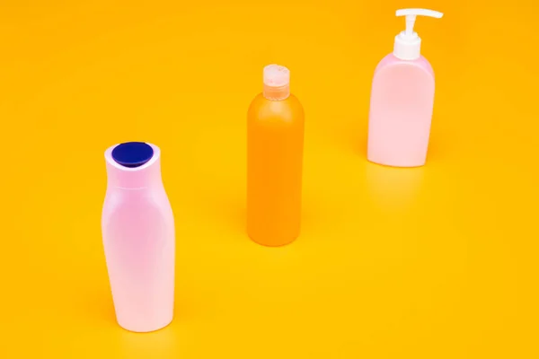Wygodnie ukształtowane pojemniki. Butelki kosmetyczne w rzędzie. Butelki wielokrotnego napełniania żółte tło — Zdjęcie stockowe