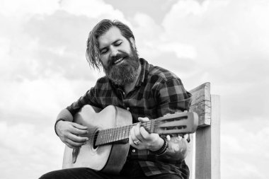 Olgun sakallı bir adam gitarist ve gitarist gibi sıradan görünüyor.