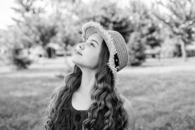 İyimser gülümseyen kız güneşli bir yaz günü parkta eğleniyor, tasasız bir ruh hali içinde.