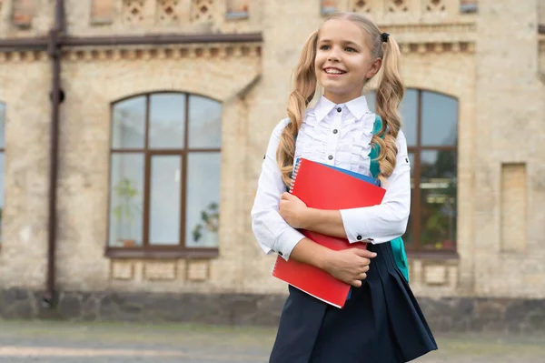 Happy szkolne dziecko w mundurze powrót do szkoły niosąc książki i plecak, przestrzeń do kopiowania — Zdjęcie stockowe