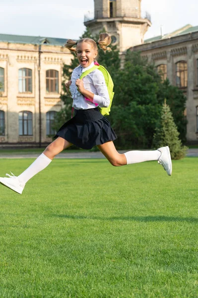 Gelukkig energiek kind in uniform met schooltas springen van vreugde, terug naar school — Stockfoto