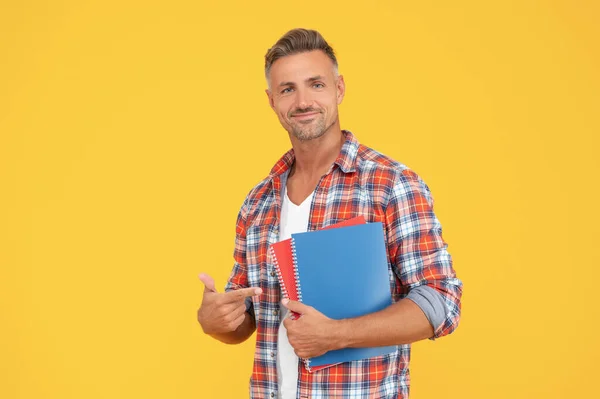 Heureux homme étudiant pointant du doigt les livres fond jaune, éducation — Photo