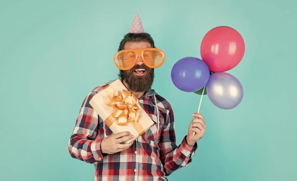 Elegante ragazzo barbuto con acconciatura alla moda indossare camicia a scacchi tenere palloncini partito e scatola presente, felicità — Foto Stock