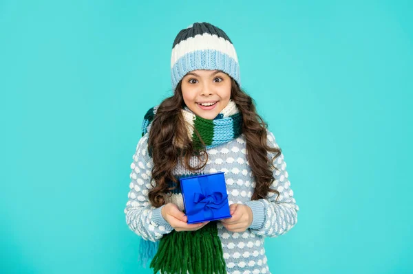 Positivt barn i stickat underklädesfodral. Grabben med present. tonåring flicka på blå bakgrund. vinterlov — Stockfoto