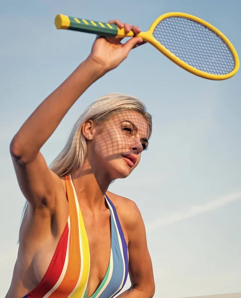 Çizgili mayo giymiş seksi vücutlu seksi bir kadın raketle tenis oynuyor, tenis oynuyor. — Stok fotoğraf