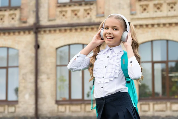 Boldog gyerek egyenruhában vissza az iskolába zenét hallgatni fejhallgatóban — Stock Fotó