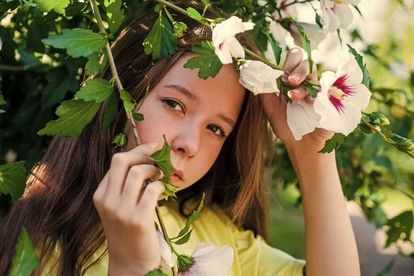 Lächelndes Teenie-Mädchen mit blühendem Hibiskusstrauch, Frühling — Stockfoto