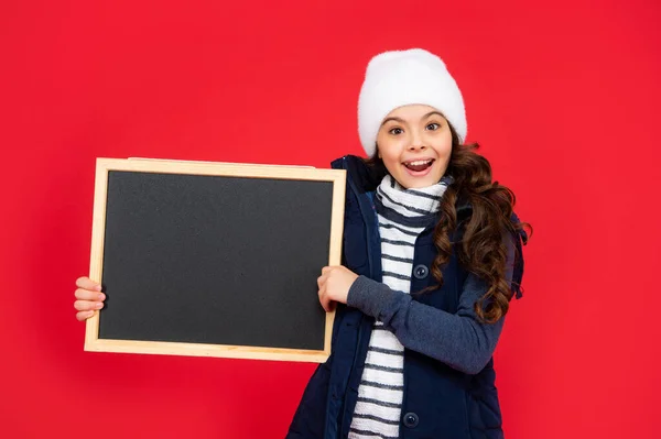 Oznámení a inzerci. zimní prodej. překvapené dítě s tabulí v klobouku. — Stock fotografie